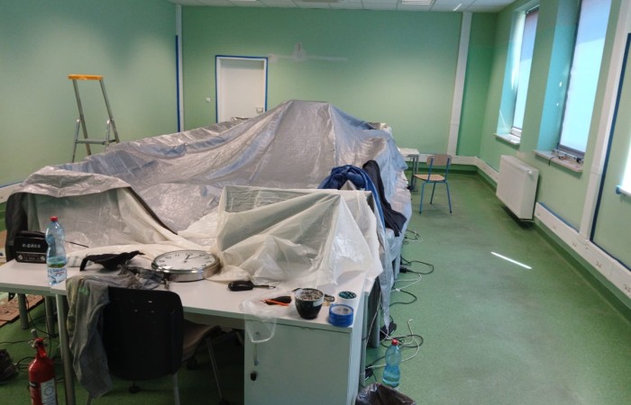 po srodku pomieszczenia meble zabezpieczone folią do malowania