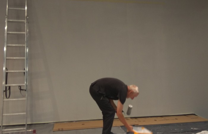 osoba nachyla się by nabrać farby na wałek